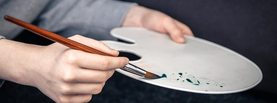 Mãos pintando com cuidado o detalhe de uma imagem sacra